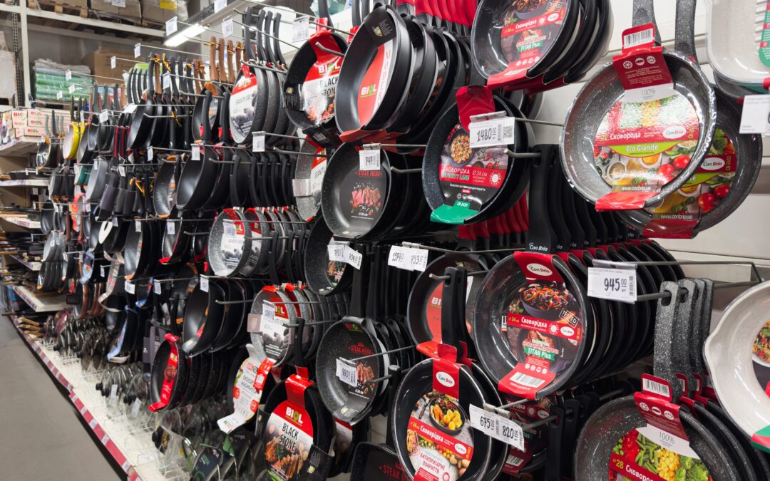 Store shelf display of various non-stick frying pans and cookware in a kitchenware aisle